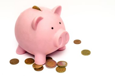 Das Bild zeigt ein Sparschwein mit mehreren Geldstücken herum.